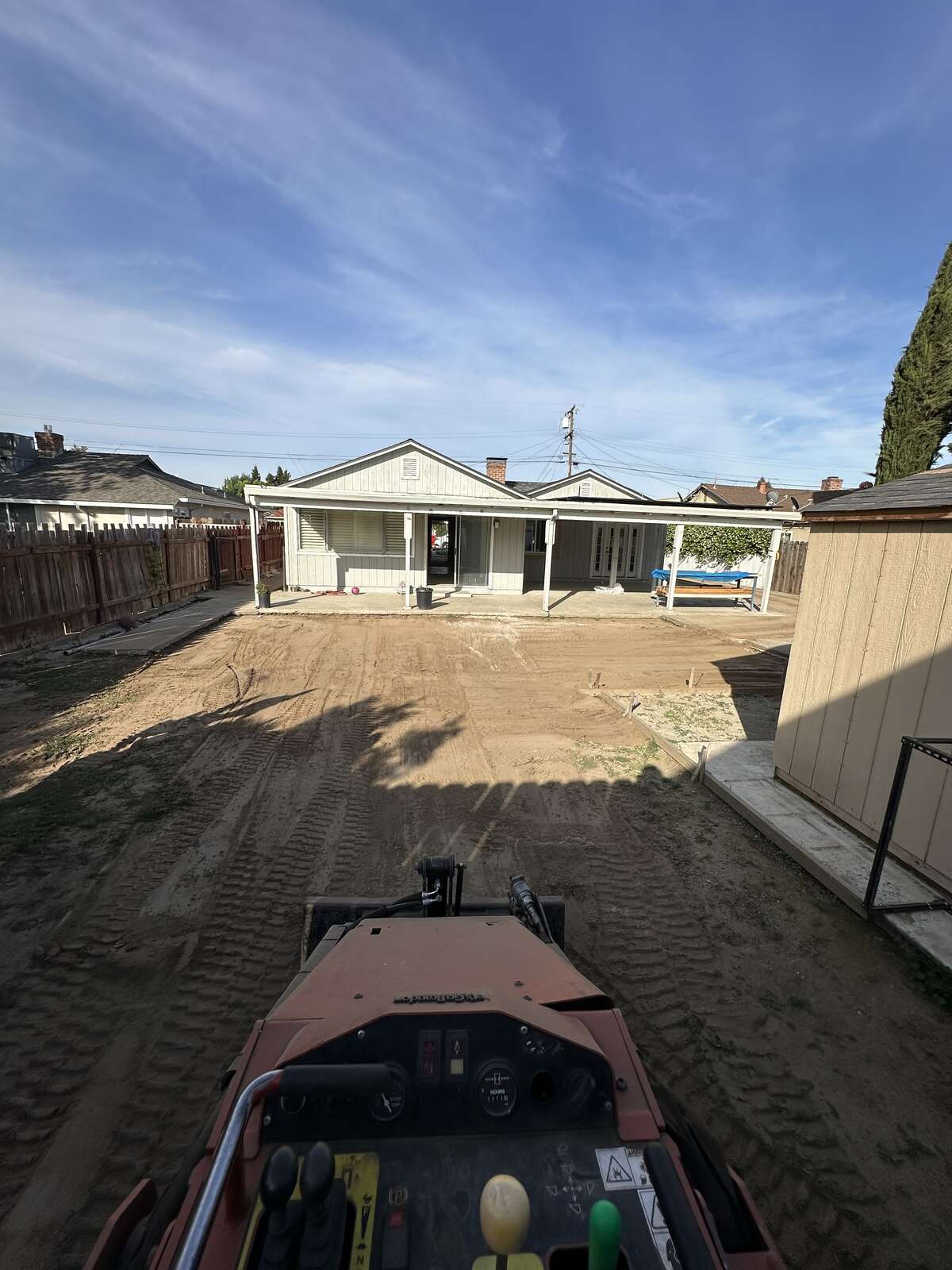 CKJ Ag Services skid steer grading a residential backyard in the Central Valley